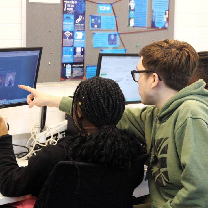 two college students look at a computer