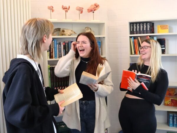 3 students laughing with books in their hands