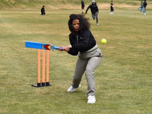 young person holding cricket bat taking a hit at the ball