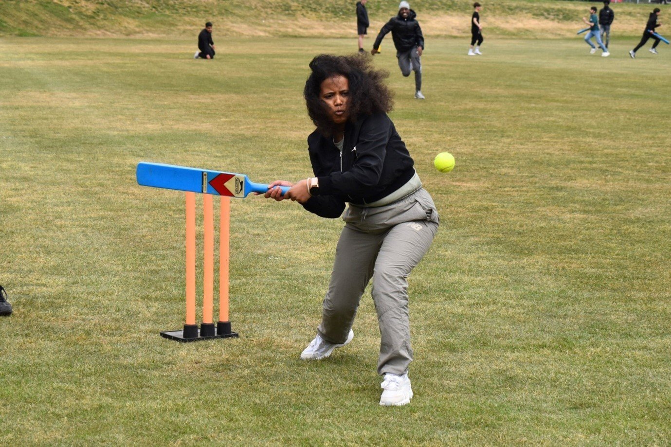 young person holding cricket bat taking a hit at the ball
