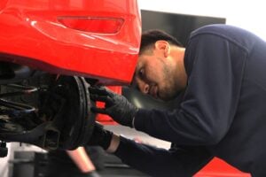 automotive student in a workshop working on a red vehicle