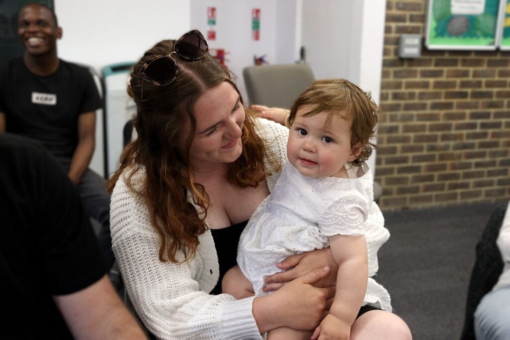 Student with baby on her lap, both smiling.