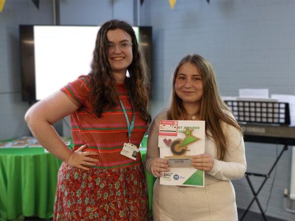 Student and presenter with award smiling at camera