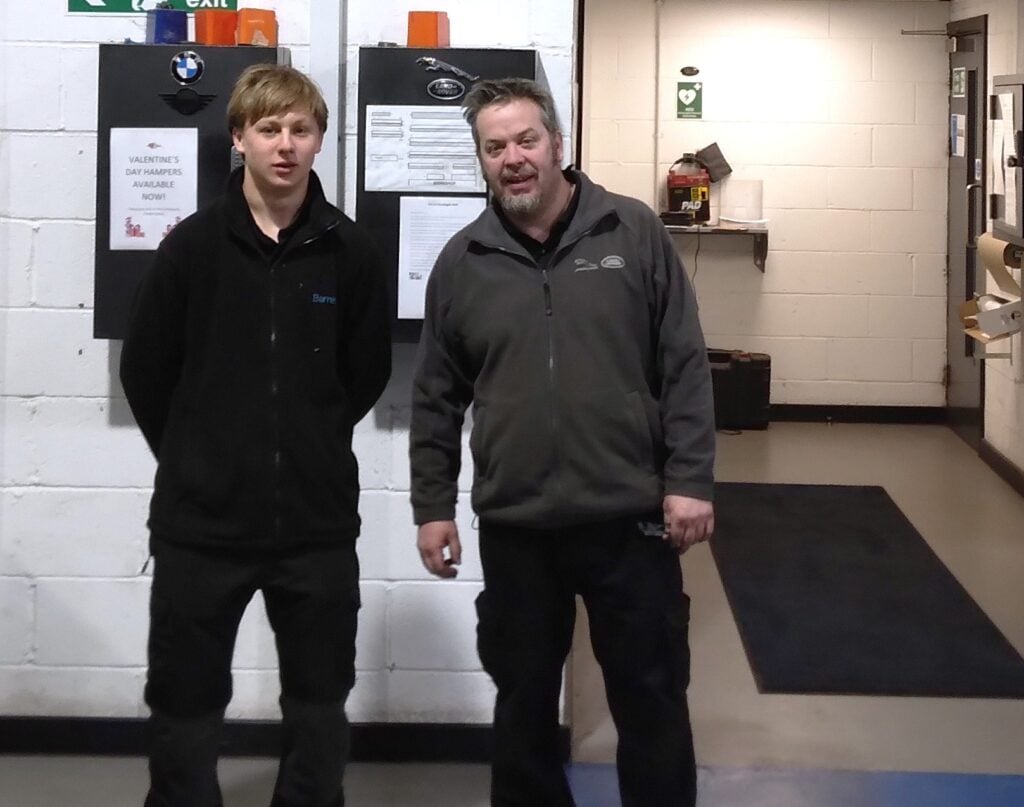 two men standing in front of a white wall