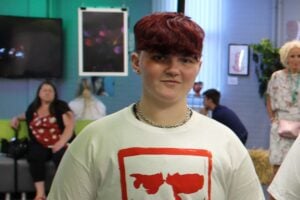 Young person with short red hair smiling at the camera