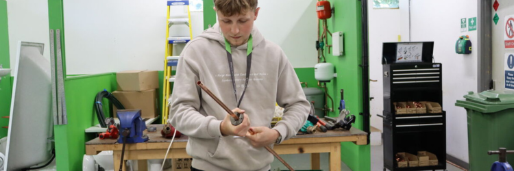 Student working with pipework at a workbench.