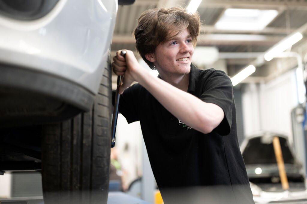 Student changing a car tire