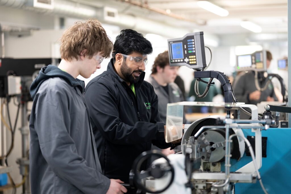 Student and tutor using machine in engineering lab