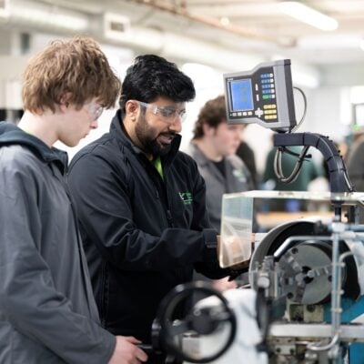Student and tutor using machine in engineering lab