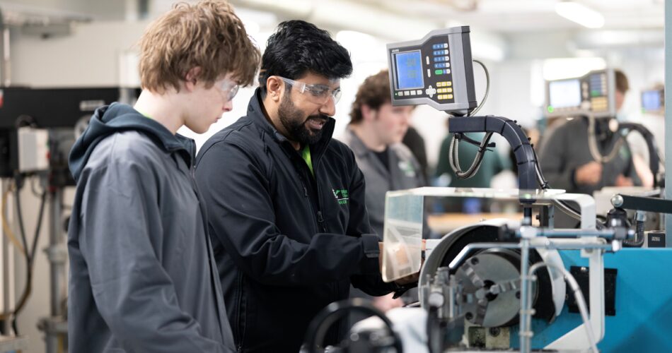 Student and tutor using machine in engineering lab