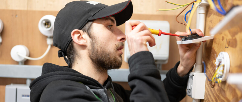 student working with screwdriver on an electrical socket board.