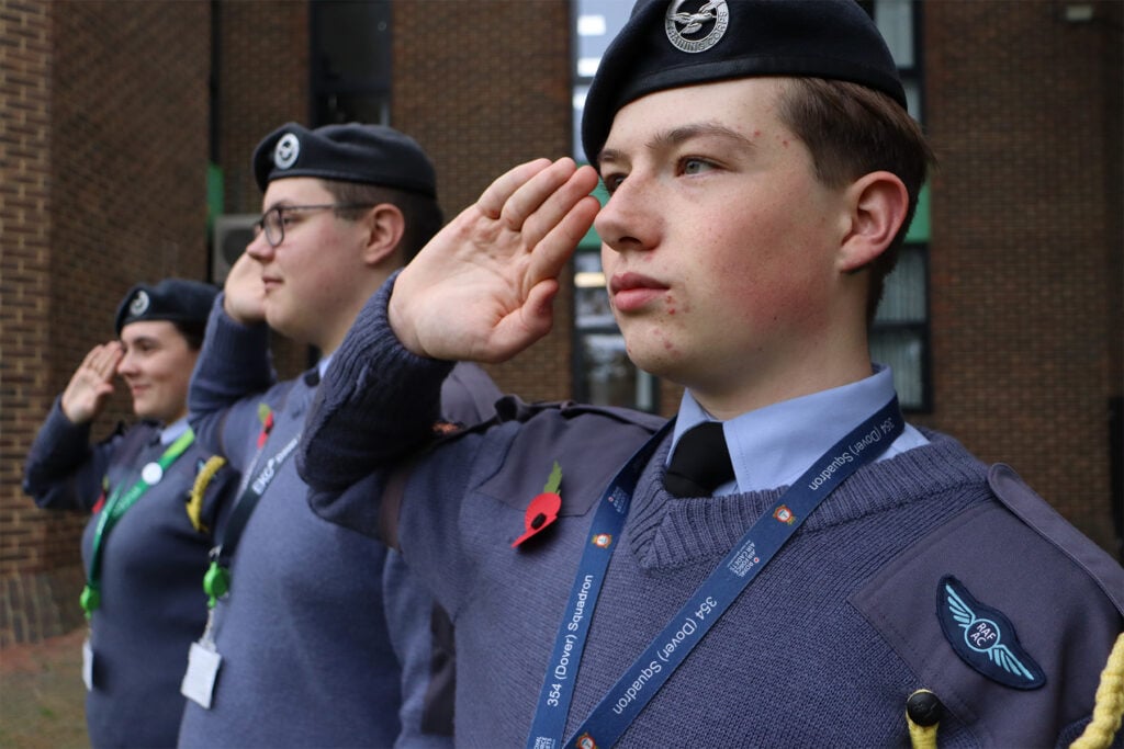 Students in cadet uniform saluting