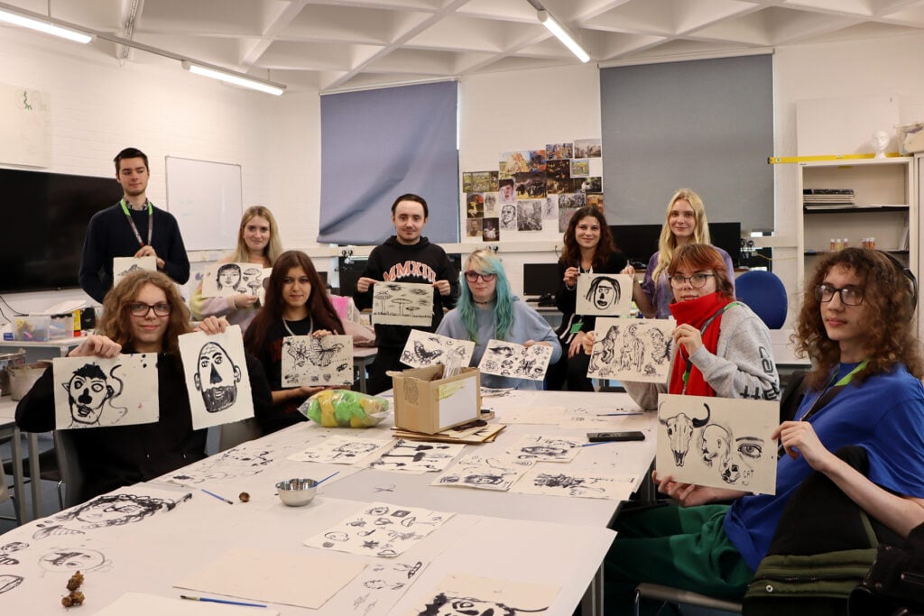Art class, a group of students holding up their sketches