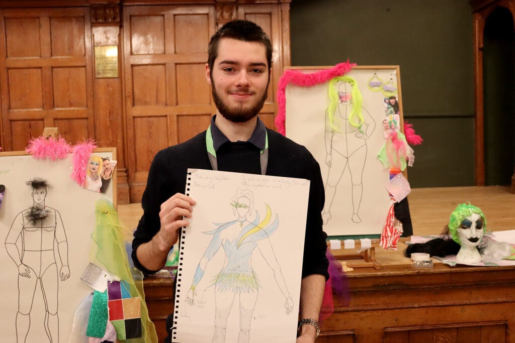 Student holding costume design poster
