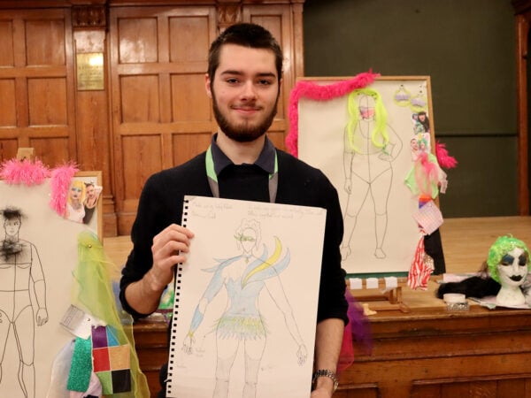 Student holding costume design poster