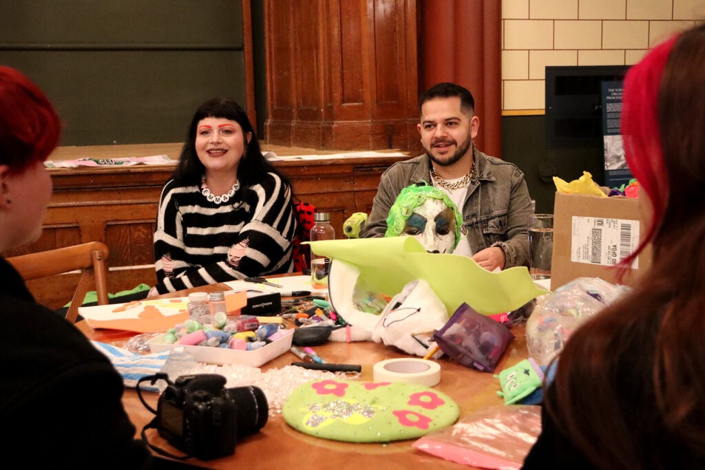 2 people sat at a table full of crafts