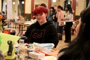 Student sat at a table surrounded by crafts