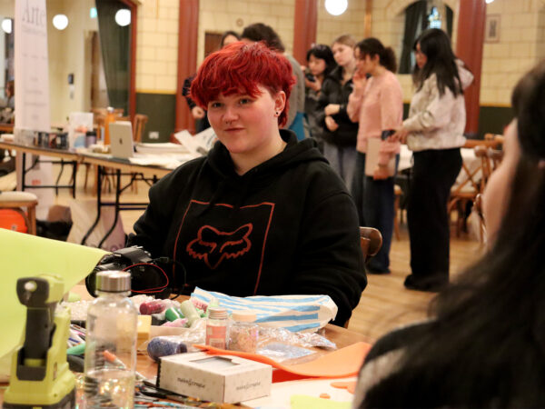 Student sat at a table surrounded by crafts