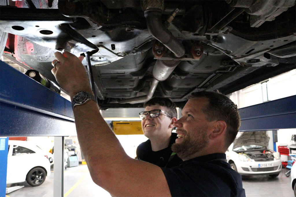 Student and tutor working under a car