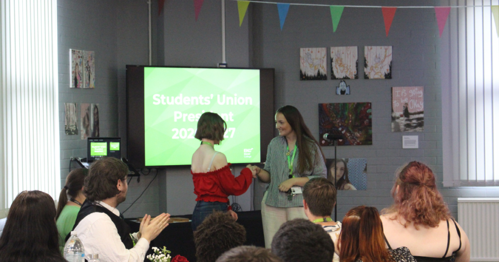 Student shaking hands with the Student Experience Officer in front of a crowd.