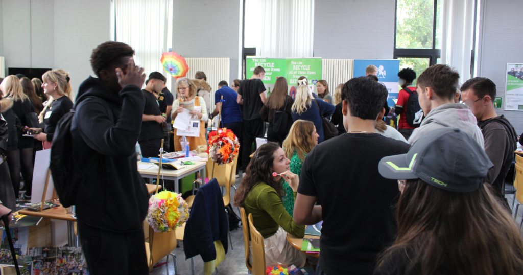 The refectory area at Dover College full of students walking around with charities and businesses on various tables.
