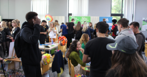The refectory area at Dover College full of students walking around with charities and businesses on various tables.