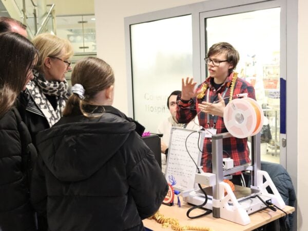 a college student speaks to member of the public about his 3D printer.