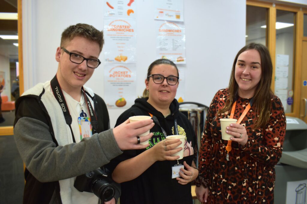 3 people smiling at the camera holding a hot drink