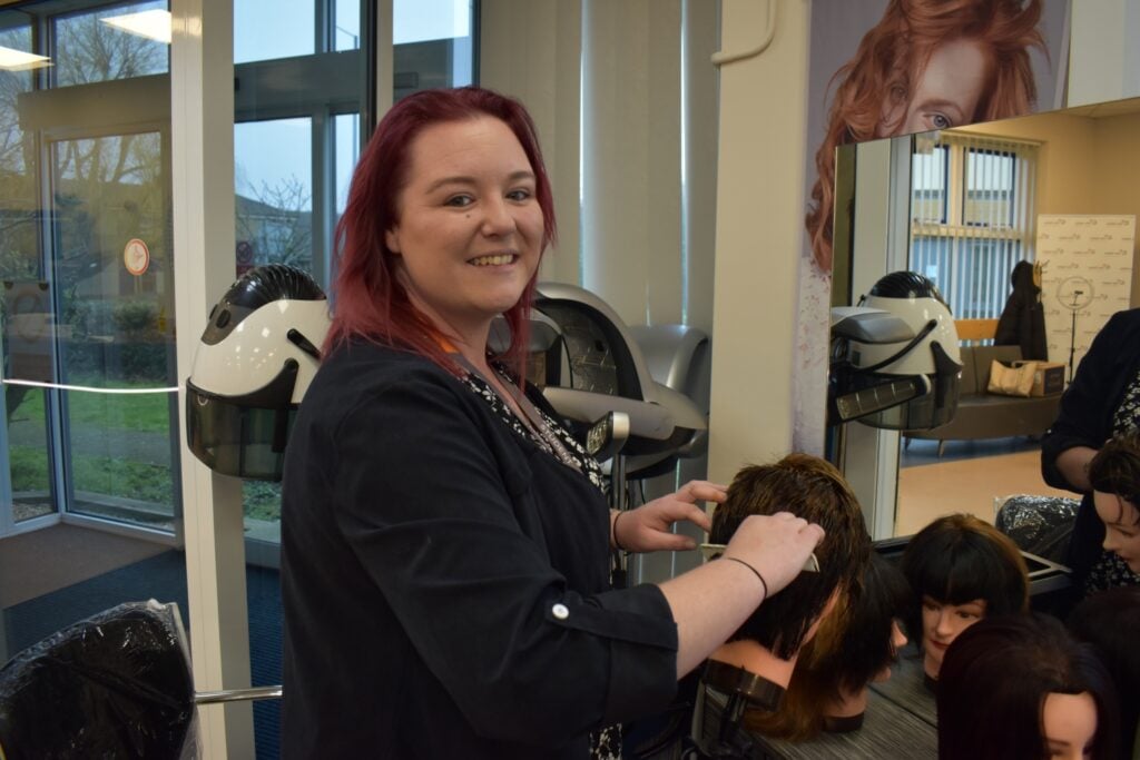 adult hairdressing student works on client's hair