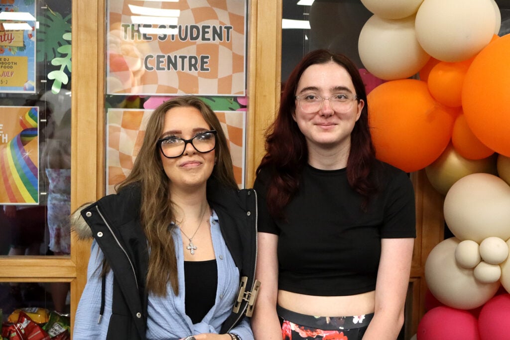 2 young women smiling a camera standing next to lots of balloons