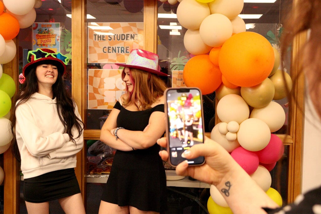 A smart phone taking a photo to 2 woman posing