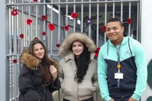 Lily, Honey and Business student, Rio, standing by the poppy display at the station.