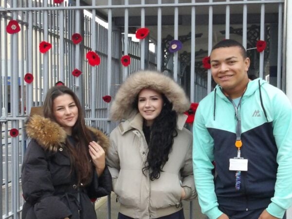 Lily, Honey and Business student, Rio, standing by the poppy display at the station.