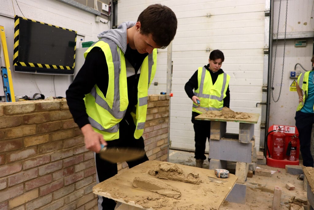 Students picking up much ready to lay a brick