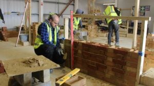 Bricklaying student plumbing the wall with a spirit level