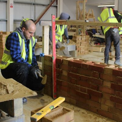 Bricklaying student plumbing the wall with a spirit level