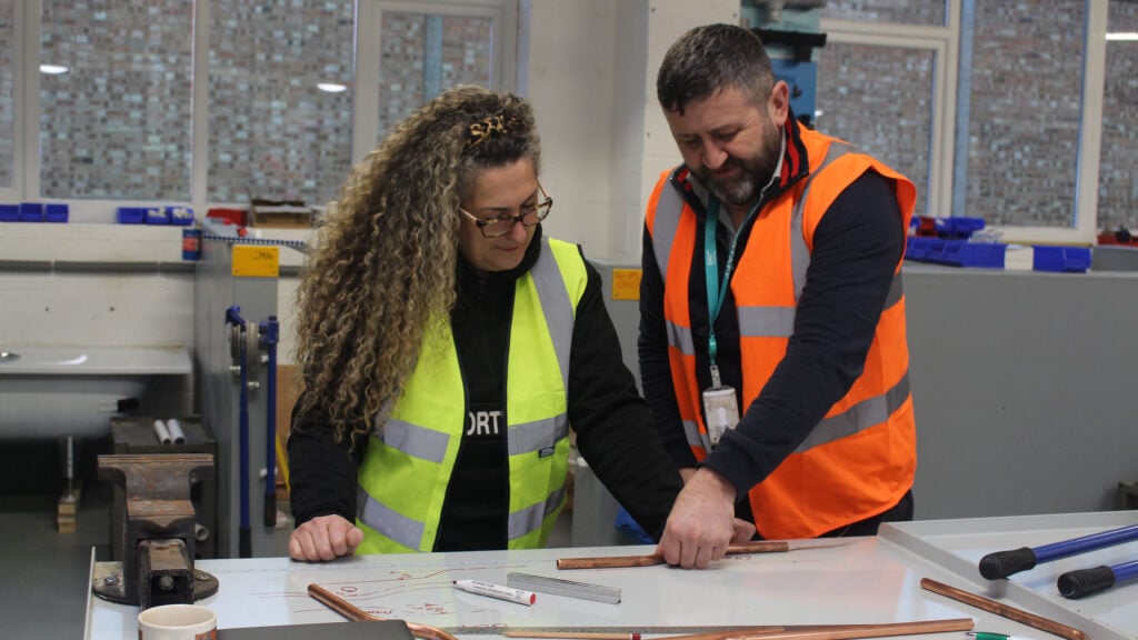 Student working with teacher on a plumbing assignment