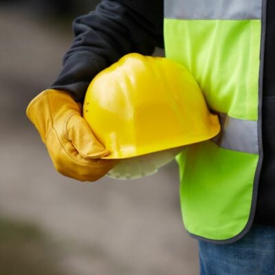 person holding yellow hard hat with a fluorescent high-vis jacket