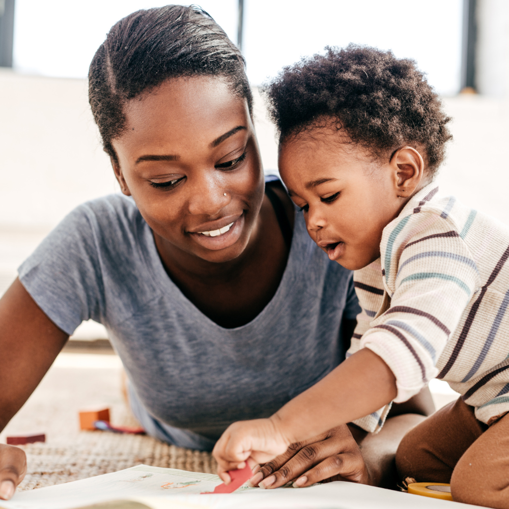 A lady helping a toddler with a craft activity in a nursery.