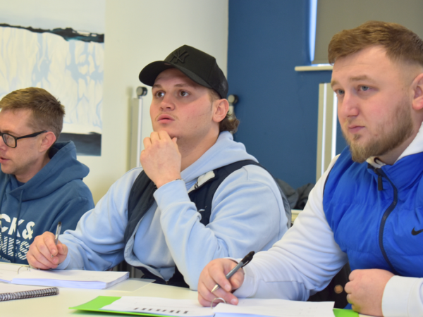 Three students sat in a classroom working