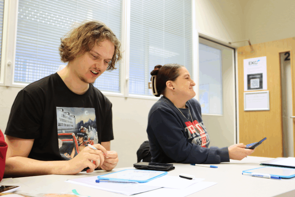 one male student and one female student studying at a desk and laughing