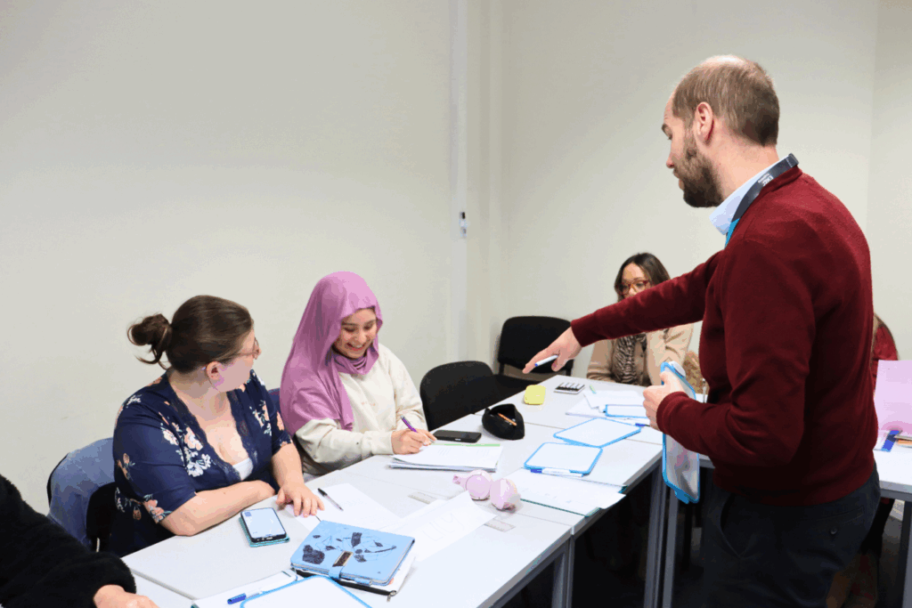 a male teacher points at a female student in a classroom