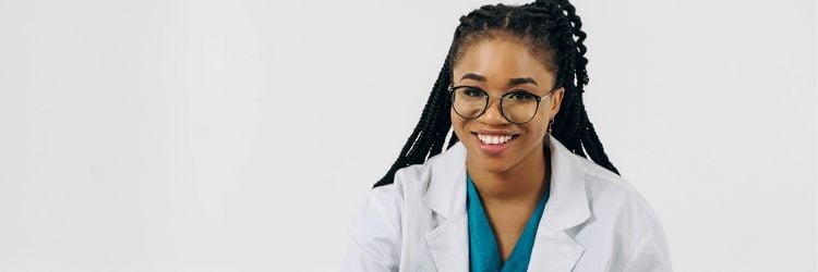 woman wearing scrubs holding an ipad smiling at the camera.