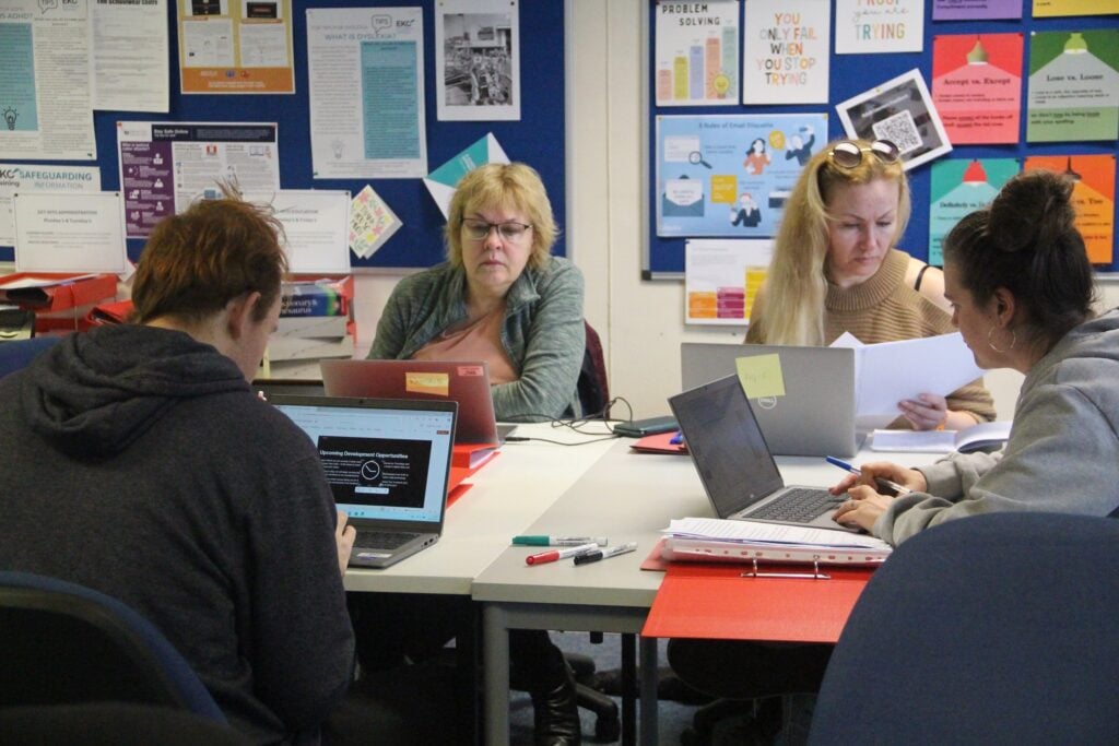 adult learners with laptops sat in a classroom