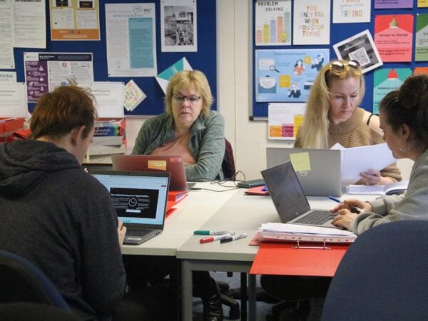 adult learners with laptops sat in a classroom