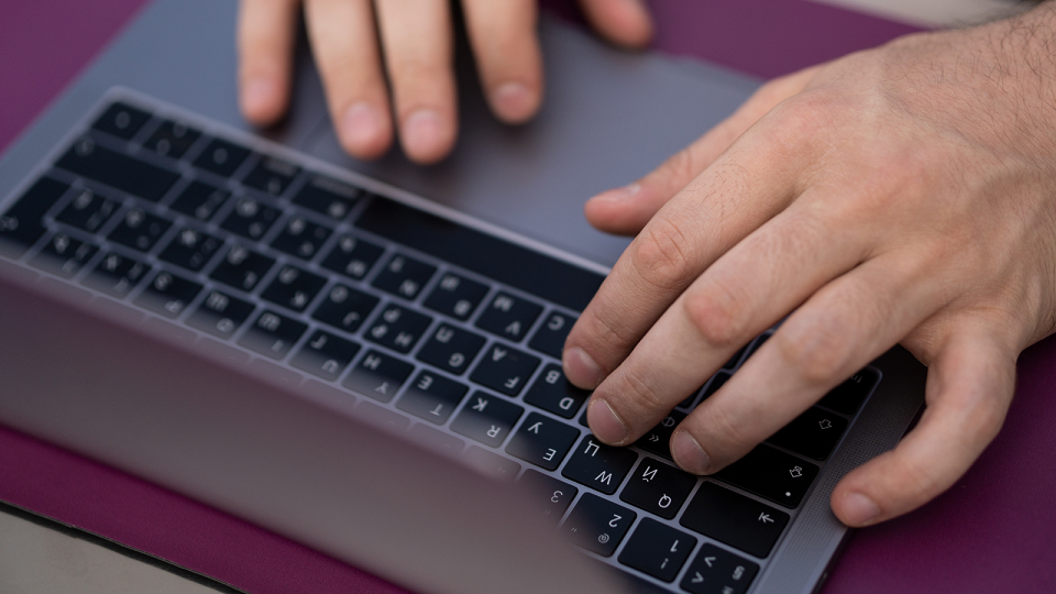 close up of hands typing on a laptop keyboard