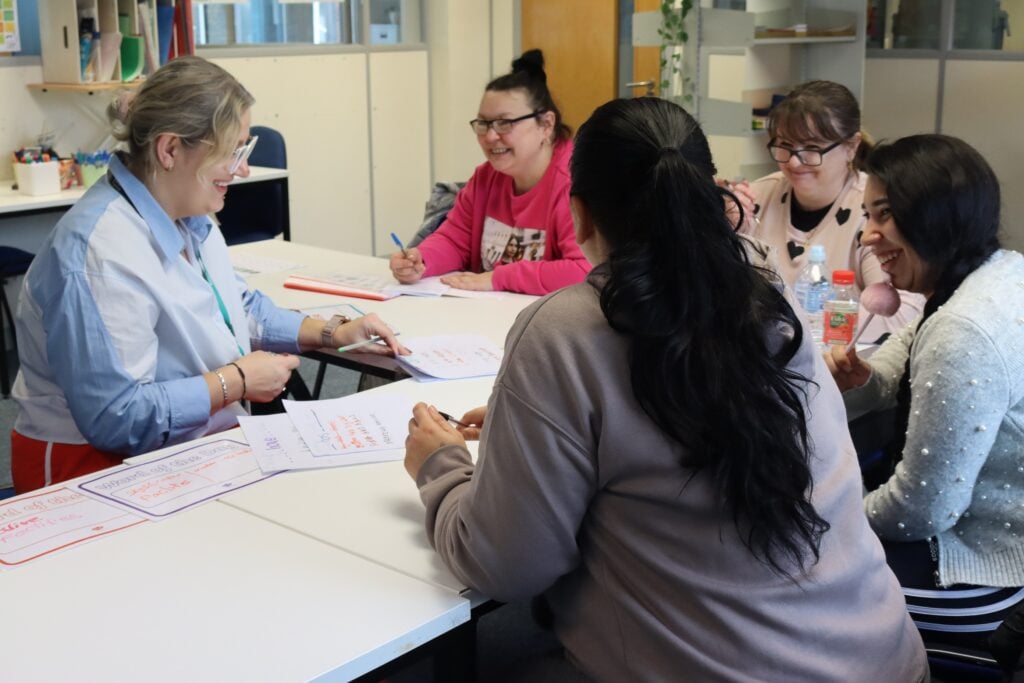a group of adult learners talking around a table