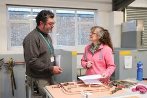 Techer and student in plumbing workshop laughing together
