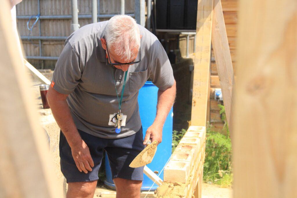 Mark bending down to lay a new brick