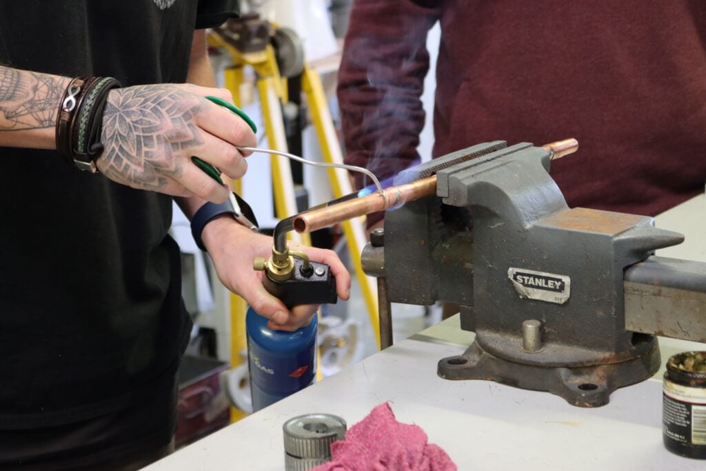 close up photo of someone soldering copper pipe